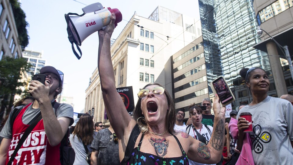 Une femme brandit un porte-voix et un cellulaire lors d'une manifestation.