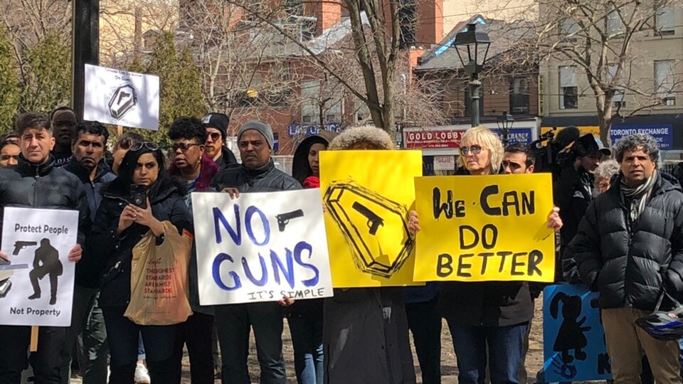 Photo de personnes tenant des pancartes disant « pas d'arme » et montrant une arme sur un cercueil