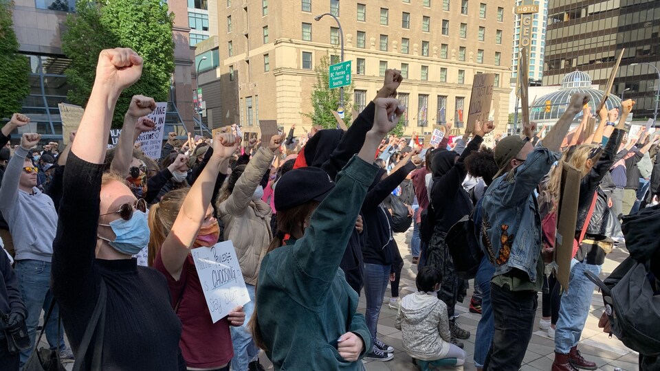 Des manifestants, la plupart masqués, lèvent le poing.