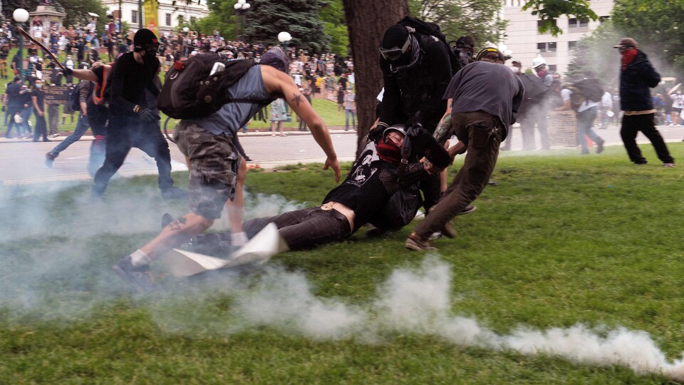 Un manifestant blessé est tiré sur le gazon sous une pluie de gaz lacrymogène.
