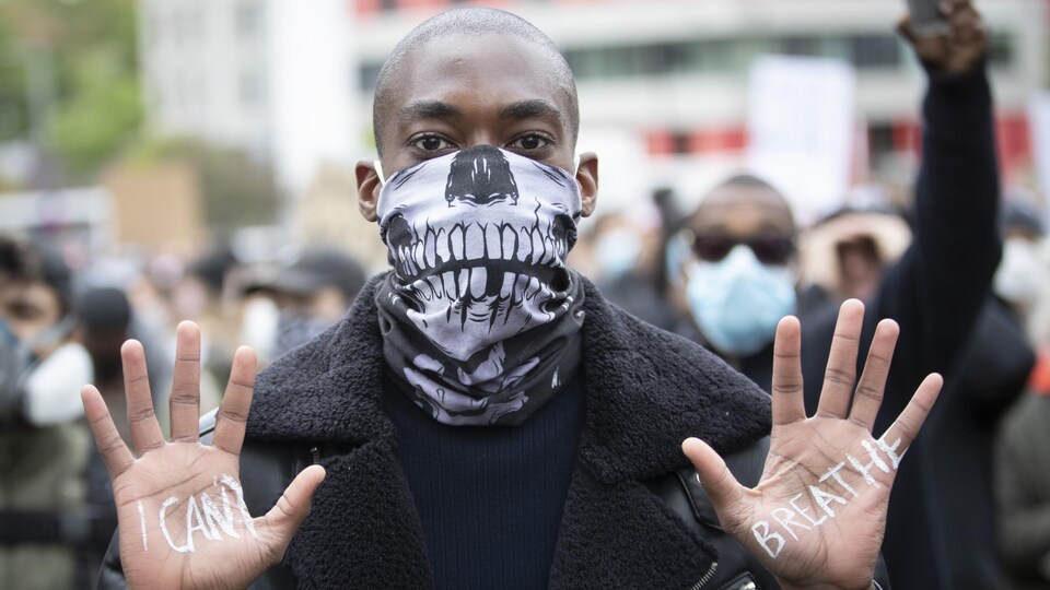 Un homme noir montre les paumes de ses mains où il est écrit « Je ne peux respirer ».