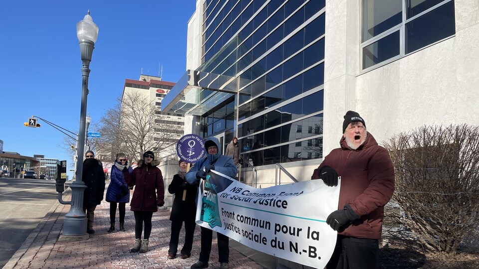 Des manifestants sur une rue du centre-ville, banderole à la main.