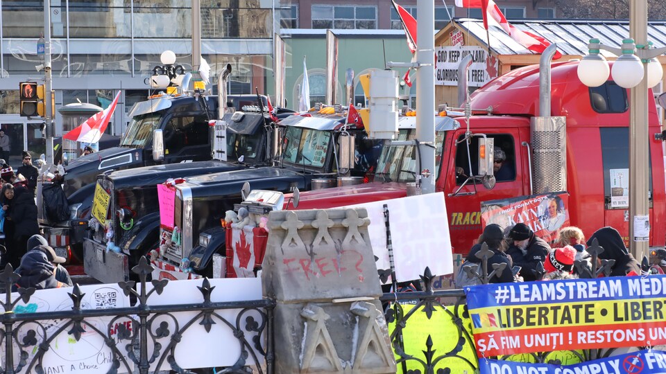 Des camions stationnés au milieu de la rue avec des affiches et des drapeaux lors d'une manifestation.