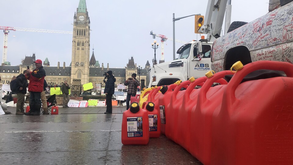 Des bidons de carburant sont alignés devant un camion en face du parlement d'Ottawa.