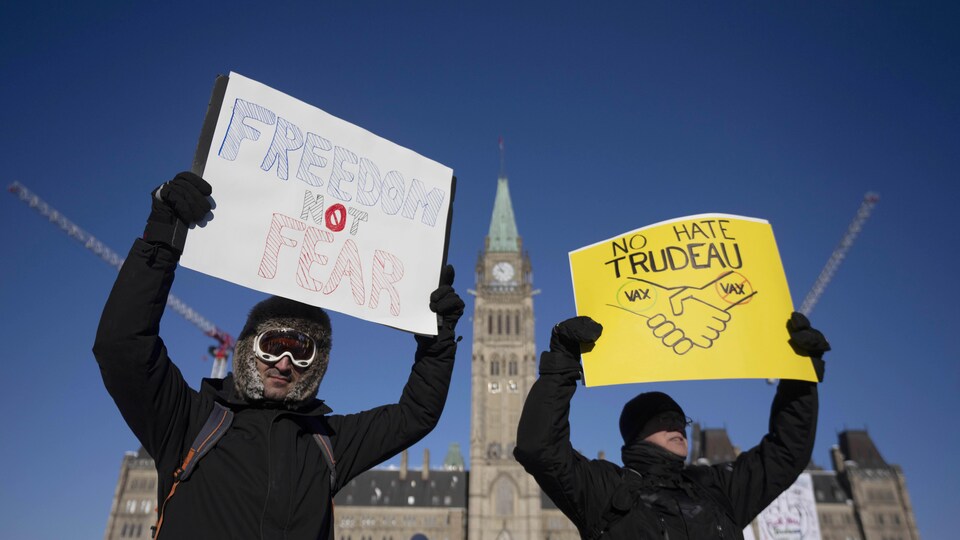 Two people put up boards in front of the parliament in Ottawa.
