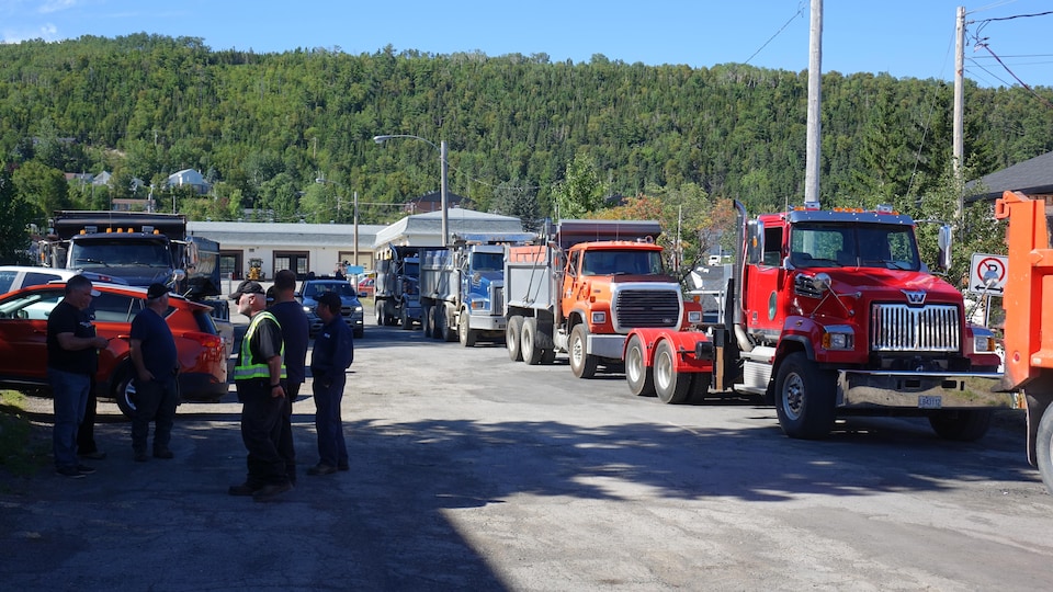 Des camionneurs et des camions stationnés se trouvent devant les bureaux de Gaspé du ministère des Transports du Québec.