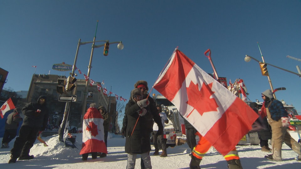 Des manifestants rassemblés avec des drapeaux du Canada.