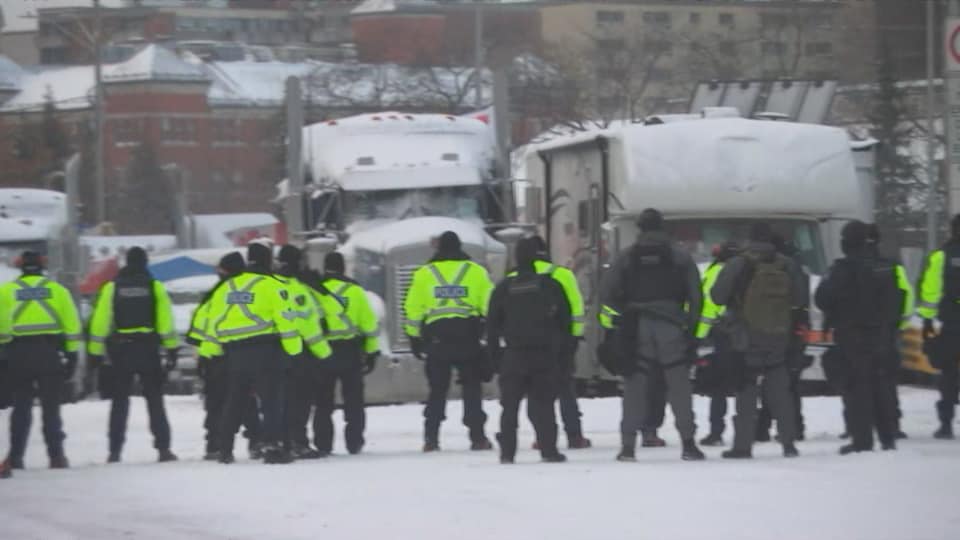 Des policiers devant des camions.