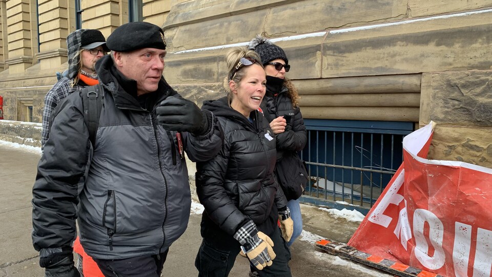 Quatre personnes marchent dans la rue.