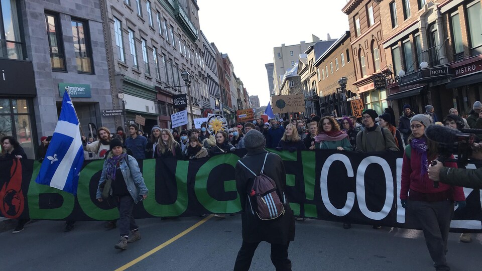 Des manifestants défilent dans la rue Saint-Jean, brandissant des pancartes qui demandent plus d'actions pour lutter contre le réchauffement de la planète.