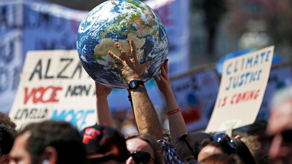 Des gens manifestent et tiennent une planète.