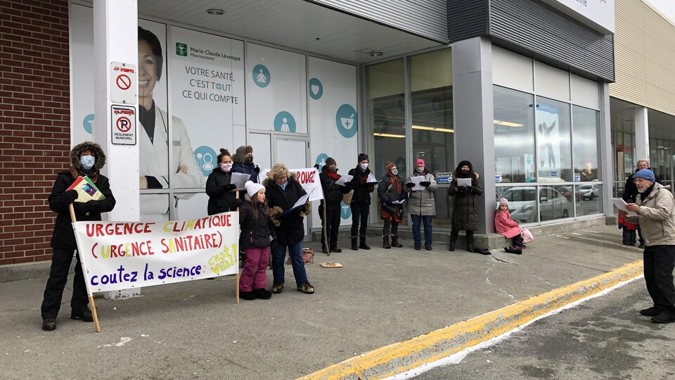 Plusieurs personnes debout, des banderoles en main