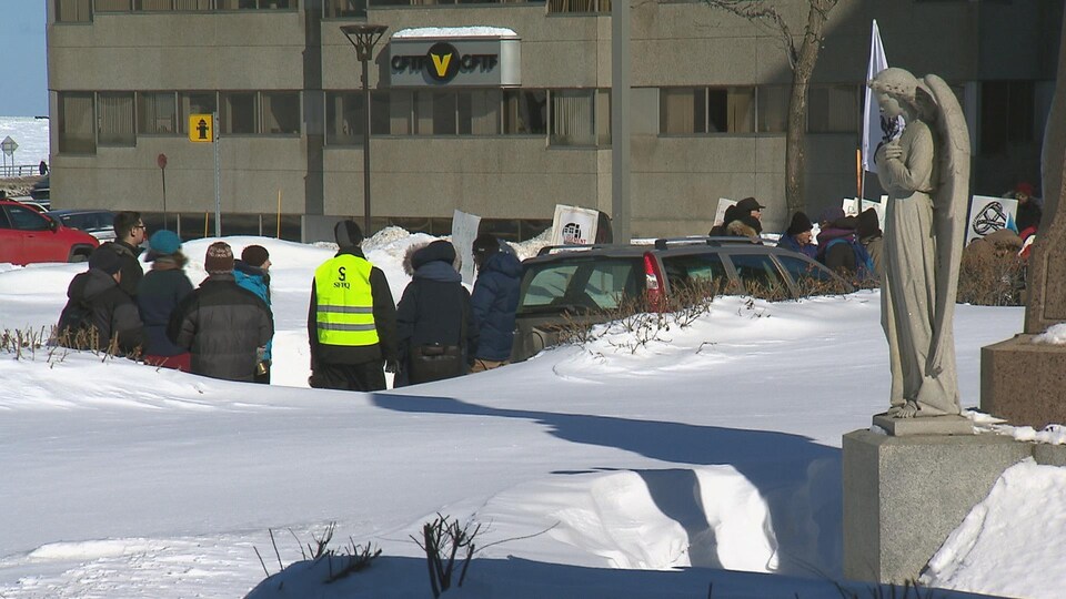 Des manifestants bordent une route devant l'église de Rimouski.