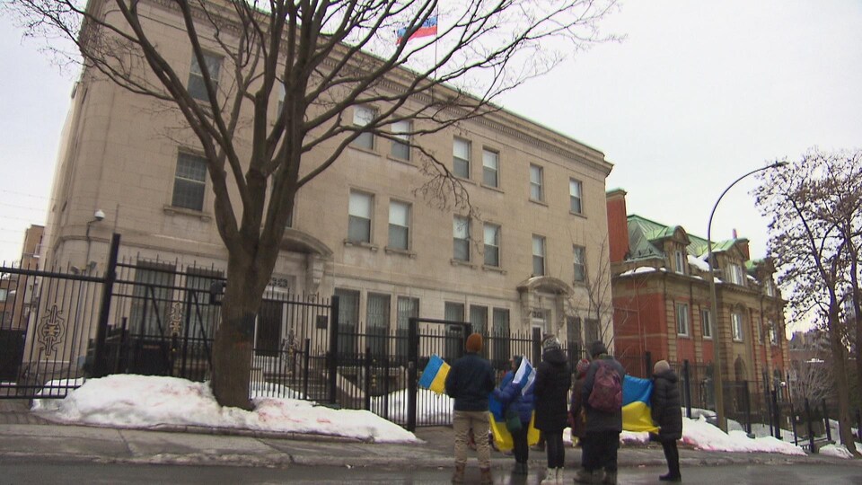 Une dizaine de personnes agitent des drapeaux ukrainiens devant le consulat général de Russie à Montréal.