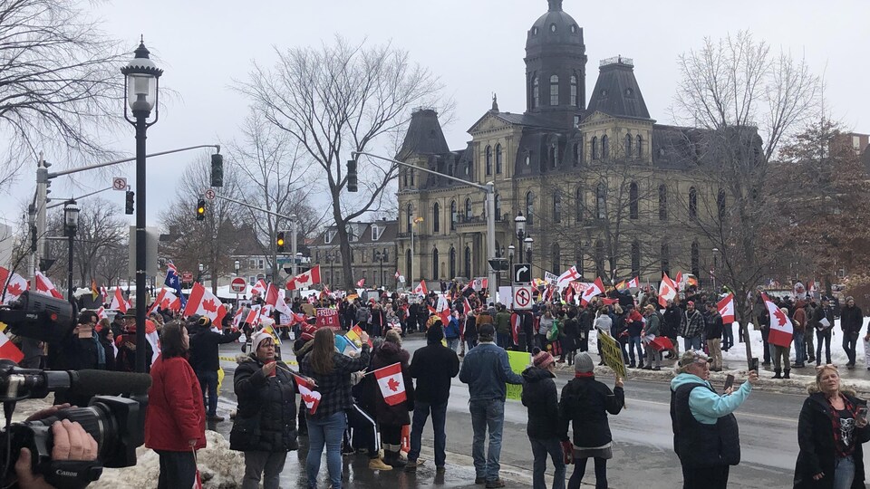 Des manifestants portent des drapeaux du Canada devant l'Assemblée législative du Nouveau-Brunswick, à Fredericton.