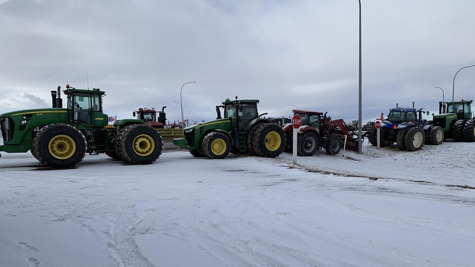Photo de huit tracteurs qui bloquent une autoroute. enneigée.