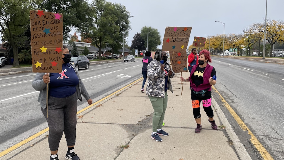 Des femmes avec des affiches à la main manifestent près d'un boulevard. 