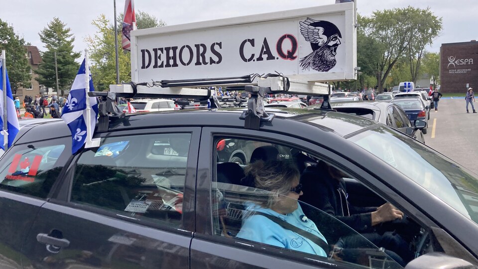 Une voiture sur laquelle on peut lire « Dehors CAQ ».