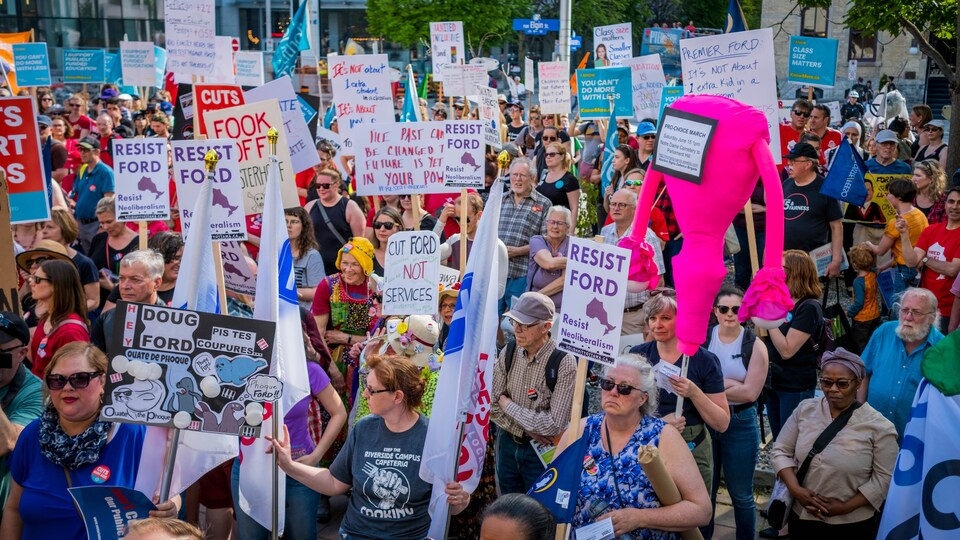 Des personnes tenant diverses pancartes lors d'une manifestation.