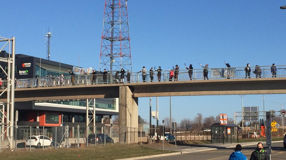 Des personnes manifestent sur un pont piétonnier. 