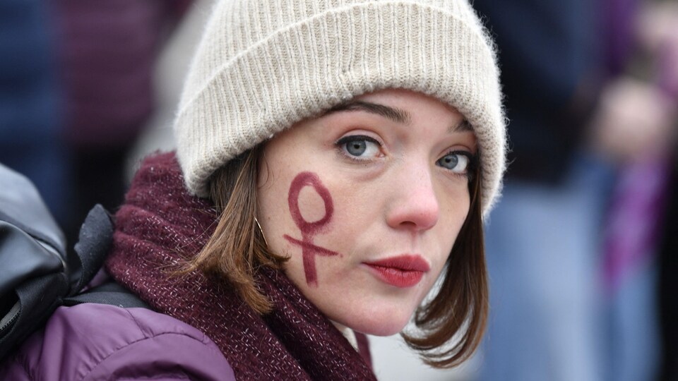 Une manifestante porte un symbole  de lutte contre la violence à l'égard des femmes.