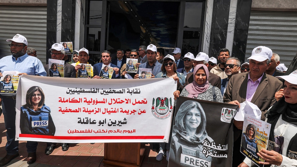 Plusieurs personnes portent des affiches avec des photos de la journaliste tuée et une banderole. 
