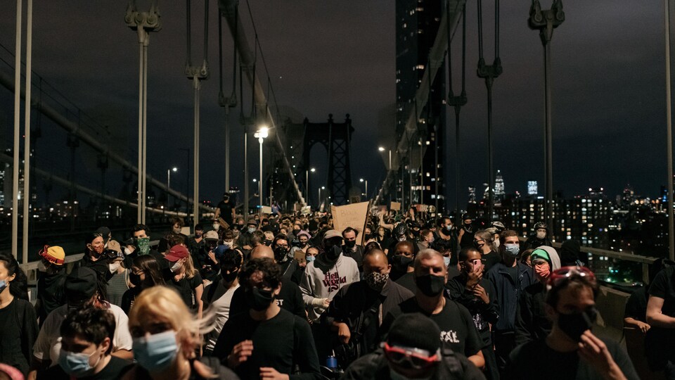 Des manifestants marchent sur le pont de Manhattan, à New York, en pleine nuit.
