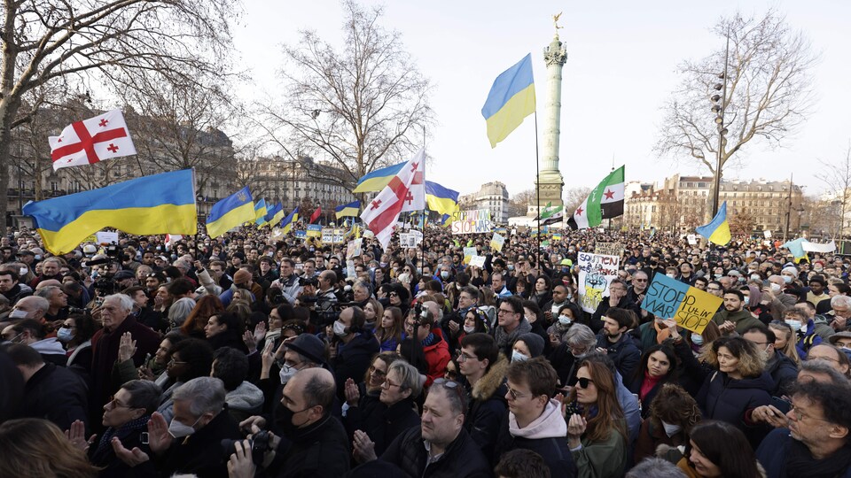 Des manifestants tiennent des drapeaux de l'Ukraine et de la Géorgie. Derrière eux se dresse le monument de la République.