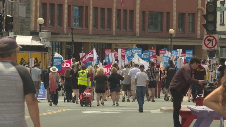Des citoyens manifestent dans la rue avec des pancartes. 