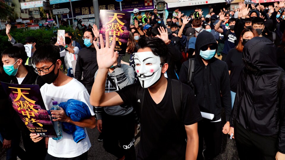 Des manifestants masqués marchent à Hong Kong.