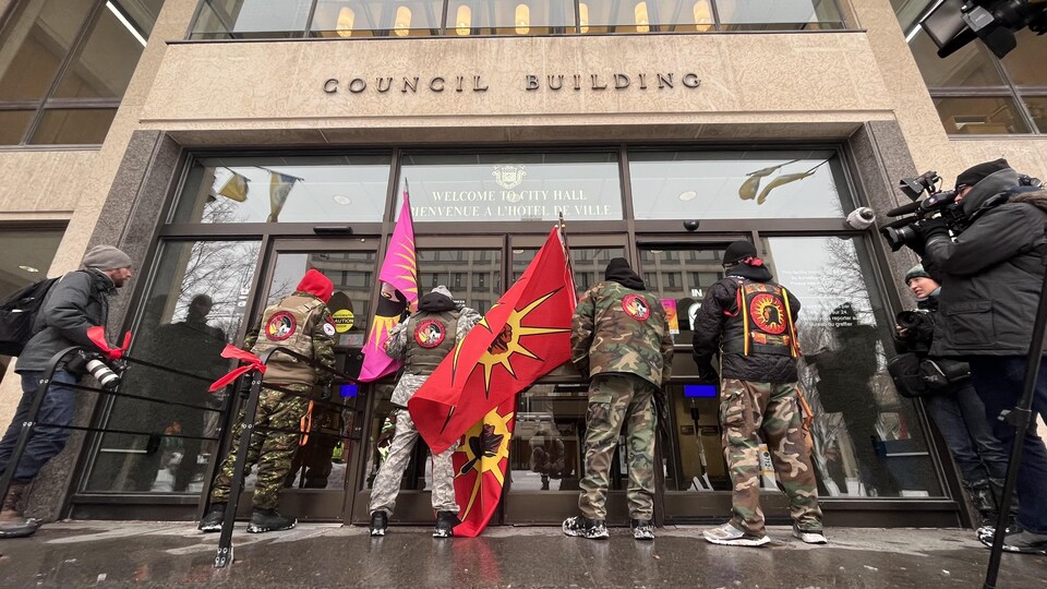 Vêtus de treillis militaires et portant le drapeau des Warriors, des manifestants ont bloqué les portes de l'hôtel de ville de Winnipeg le 15 décembre 2022.