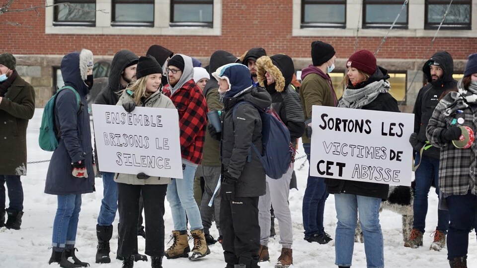 Jeunes dehors avec des pancartes où il est écrit "Ensemble, brisons le silence".                               