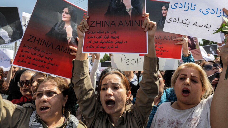  Des femmes scandent des slogans et brandissent des pancartes représentant le portrait de Mahsa Amini.