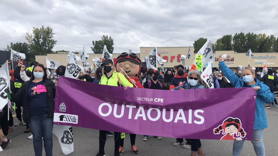 Des personnes tiennent une banderole où on lit Secteur CPE Outaouais.