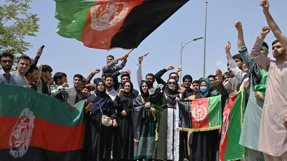 Varias personas, incluidas mujeres, ondean banderas. Muchos de ellos tienen un puño en el aire.