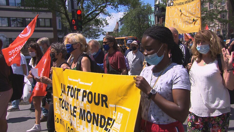 Des manifestants contre la crise du logement brandissent des bannières.