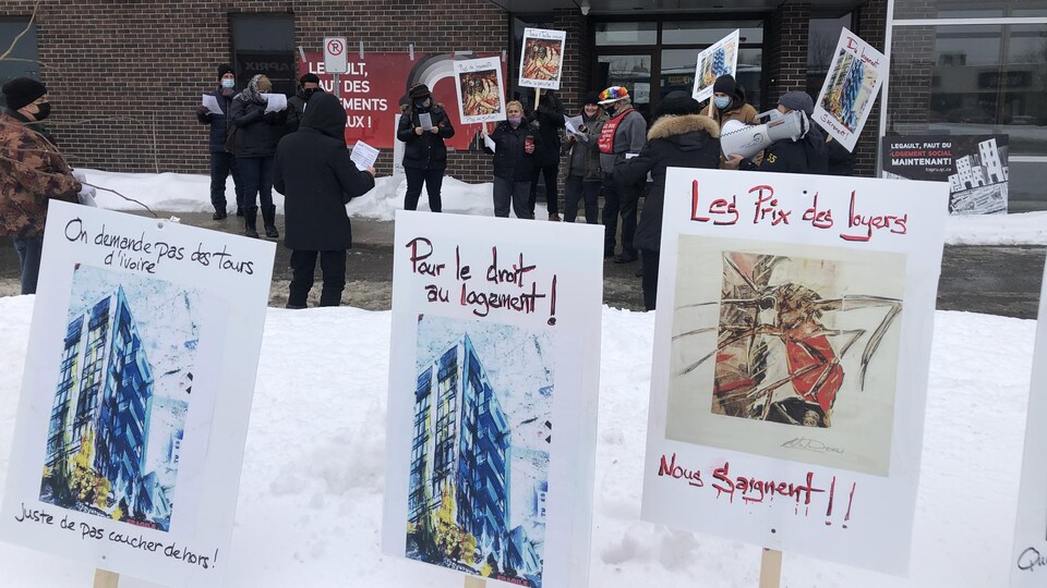 Des affiches de manifestants plantés dans la neige, devant un groupe de manifestants.