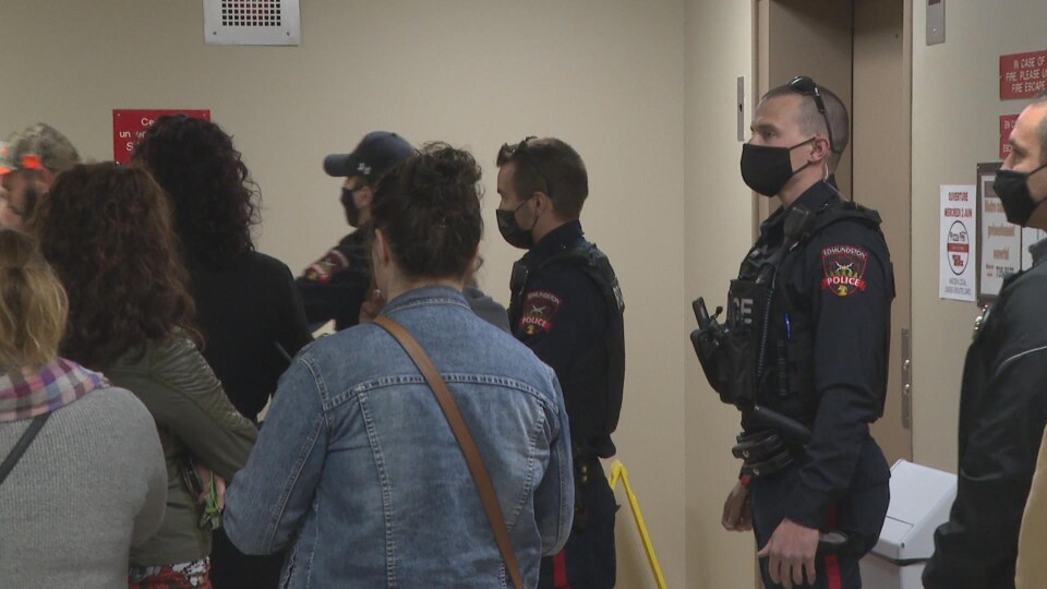 Des gens et des policiers devant des ascenseurs.