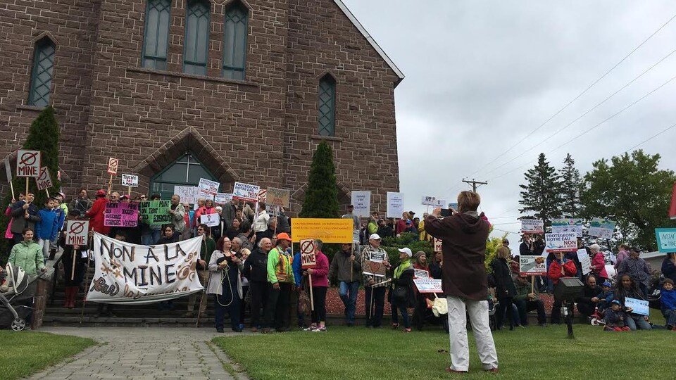Des citoyens de Grenville-sur-la-Rouge se sont mobilisés, devant l'église, samedi après-midi contre le projet minier projeté dans leur municipalité. On y voit une affiche qui dit « non à la mine ».