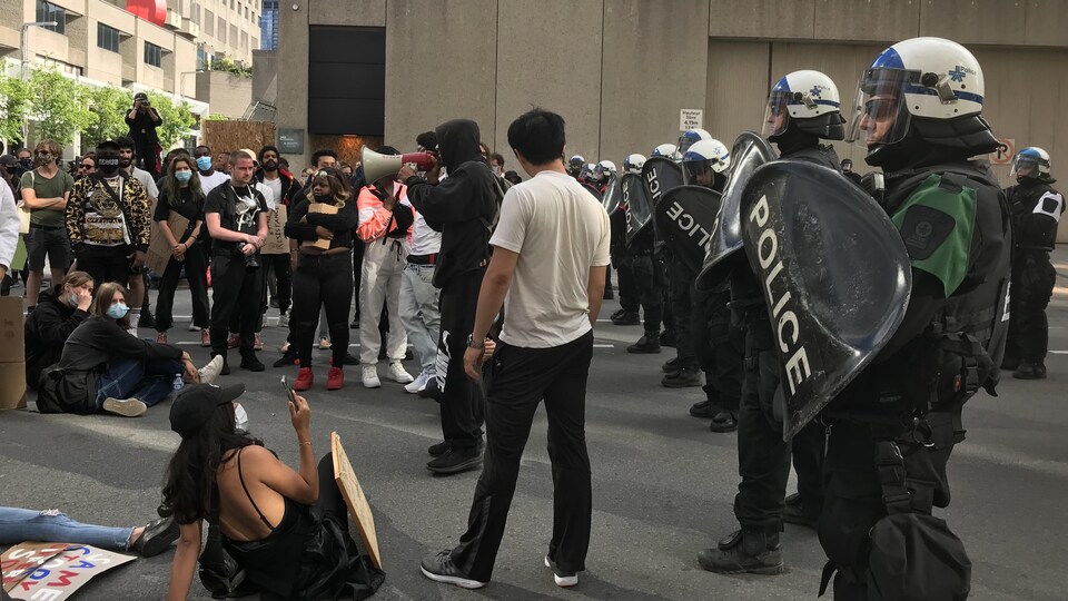 De jeunes manifestants font face à une rangée de policiers casqués de l'escouade antiémeute.