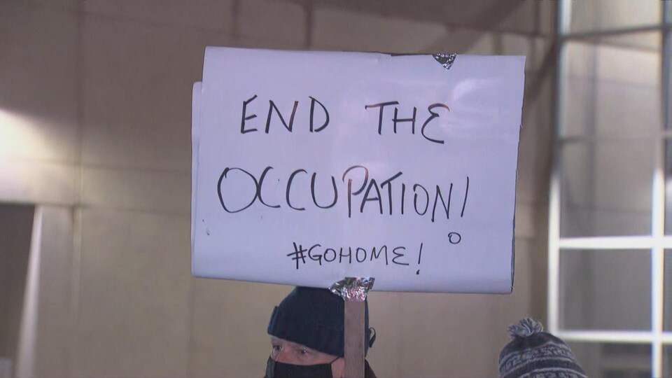 Un message sur une pancarte demande la fin de l'occupation à Ottawa.