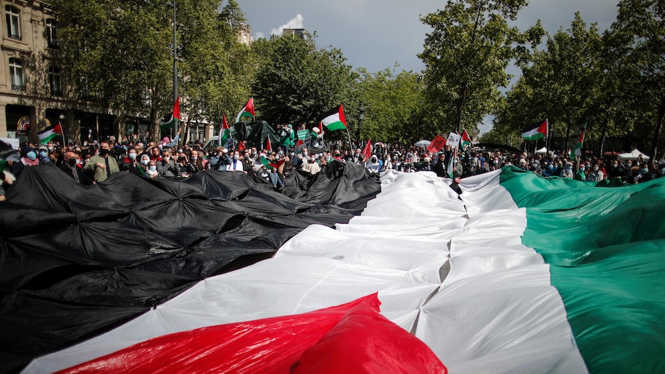 Des centaines de personnes sont massées autour d'un drapeau géant. 