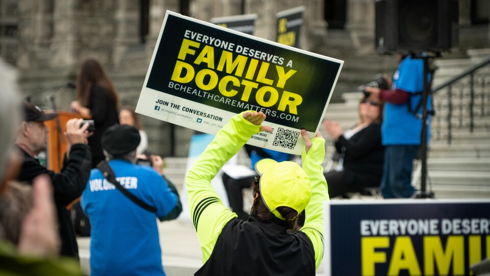 Une personne tient une affiche sur laquelle il est inscrit que tout le monde mérite un médecin de famille, lors d'une manifestation devant le parlement à Victoria, le 19 mai 2022. 