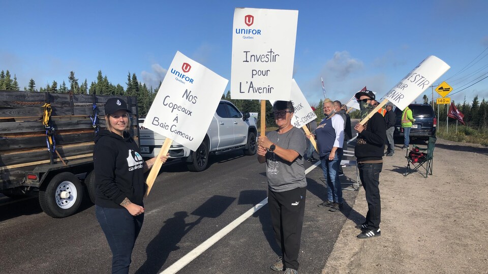 Huit manifestants tiennent des pancartes.