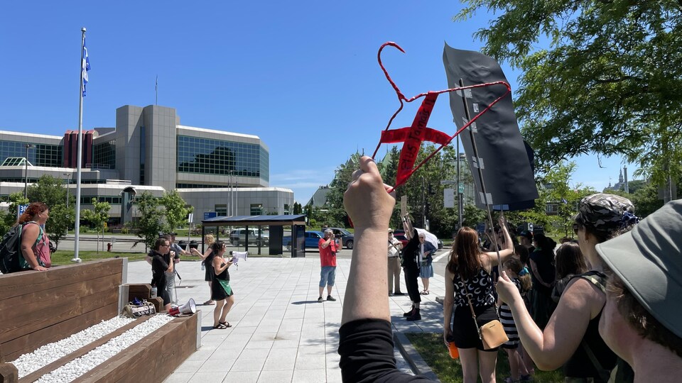 Une militante pro-choix agite un cintre rouge sur lequel est écrite la phrase « plus jamais! ».