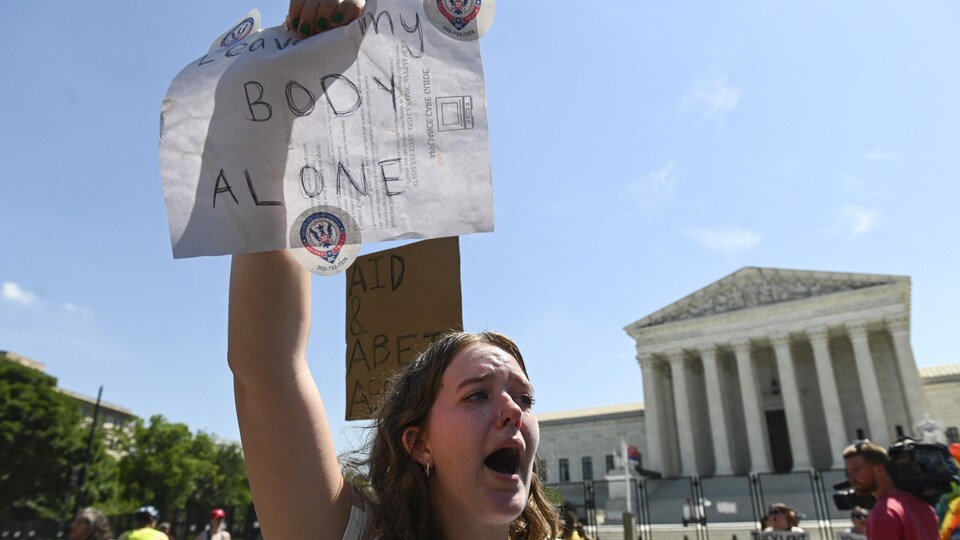 Une femme tient une affiche où il est écrit «laissez mon corps tranquille» devant la Cour suprême des États-Unis.