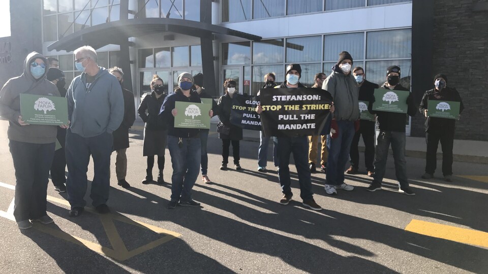 Une douzaine de personnes tiennent des affiches à l'extérieur de l'hôtel de Winnipeg où se déroule le congrès du Parti progressiste-conservateur.