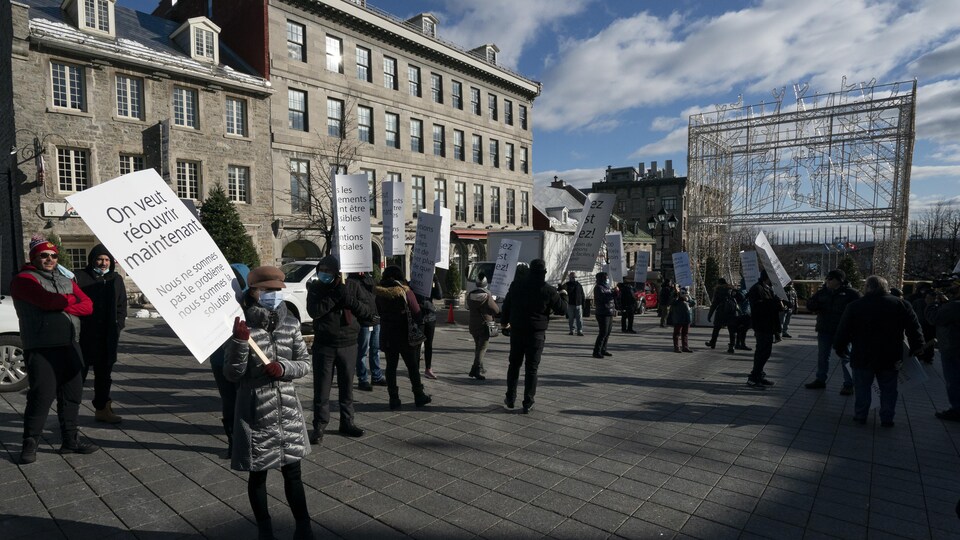 Des manifestants avec des pancartes où on peut lire « On veut réouvrir maintenant ».