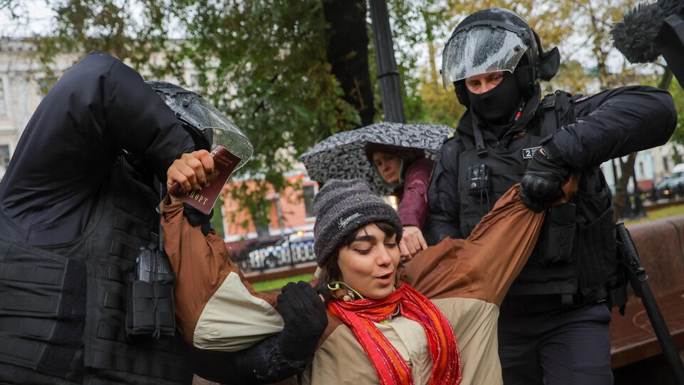 Des policiers russes détiennent une manifestante en Russie.