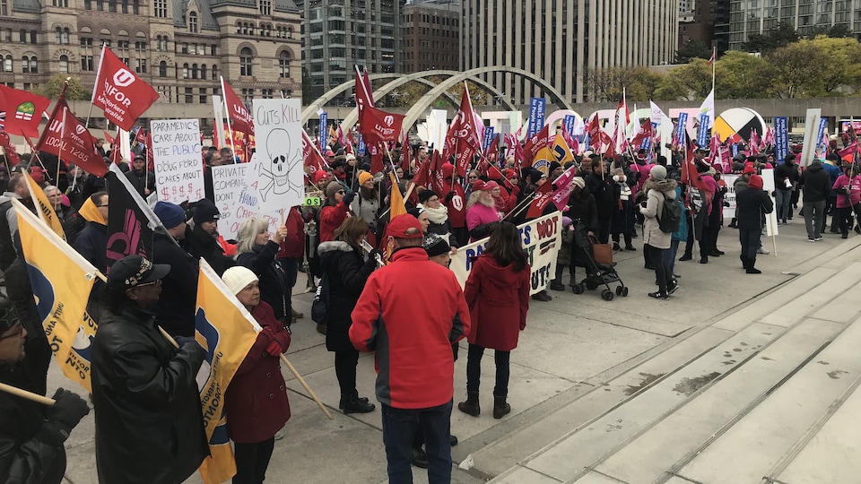 Des centaines de manifestations avec des t-shirts rouge sur une place du centre-ville de Toronto.